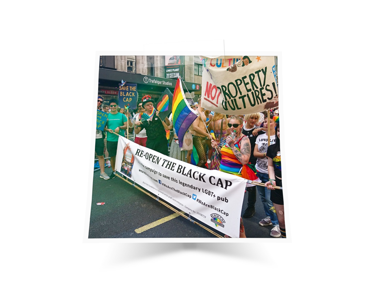 A group of people walking in the Pride March waving pride flags supporting the reopening of the Black Cap