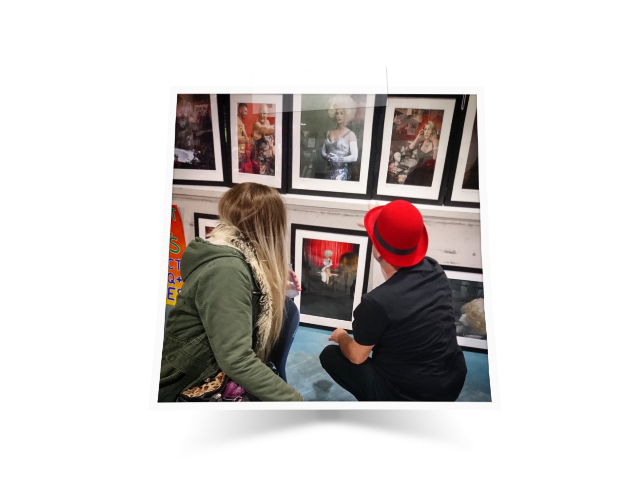 Two people sitting on the floor looking at a gallery of photographs